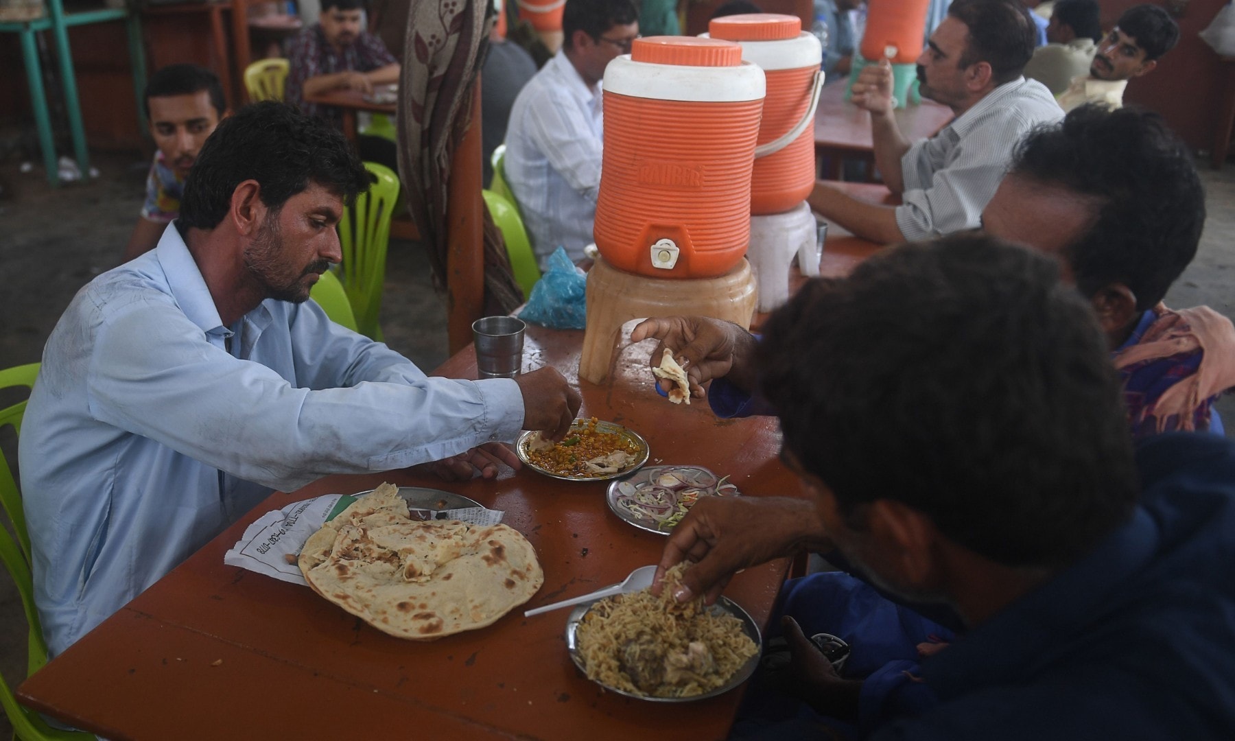 People eat at a restaurant in Karachi on August 10 after the government announced it would be lifting most of the country's remaining coronavirus restrictions. — AFP