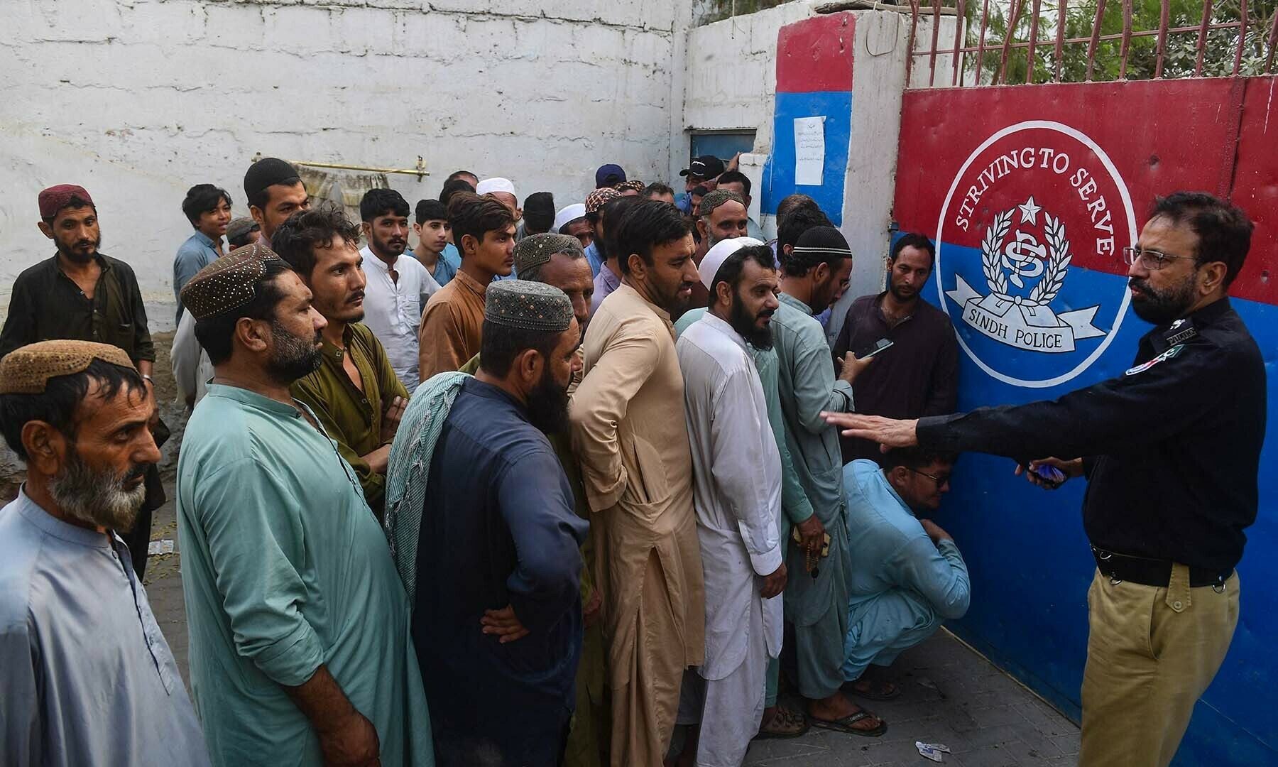 TOPSHOT - Afghan refugees queue outside a police station for their data verification by the National Database and Registration Authority (NADRA) in Karachi on November 8, 2023. More than 250,000 people have crossed from Pakistan to Afghanistan since an October ultimatum given to the 1.7 million Afghans Islamabad said were living illegally in the country. (Photo by Asif HASSAN / AFP)