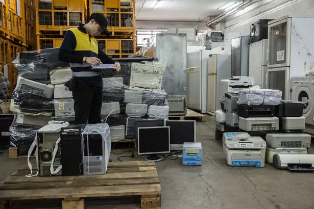 A-worker-going-through-items-at-a-a-sorting-facility-for-electronic-appliances.jpg