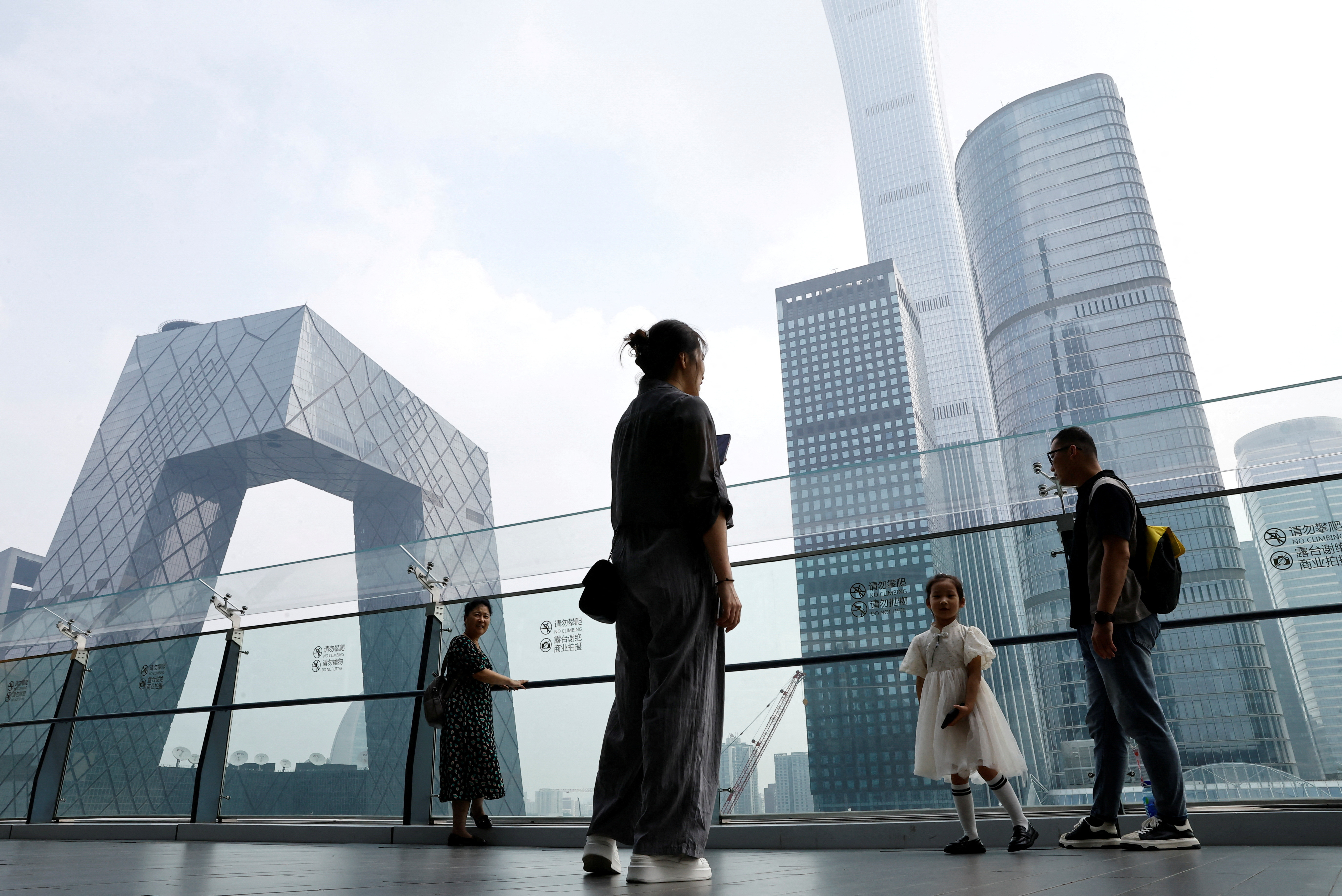 People stand at a shopping mall near the CCTV headquarters and China Zun skyscraper, in Beijing's central business district (CBD)