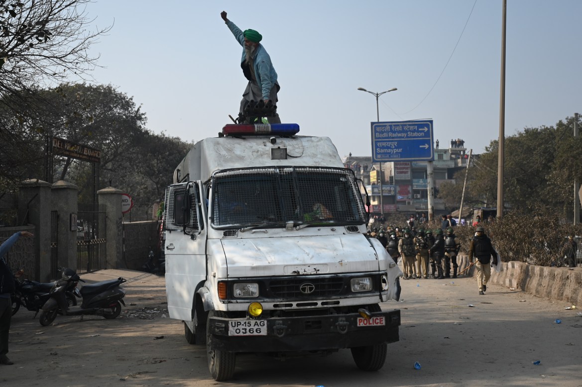 A farmer stands on the top of a police vehicle during clashes with police in New Delhi. [Money Sharma/AFP]