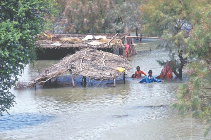  LARKANA: Residents of Azeem Bhatti village, located near Gambat along the Larkana-Khairpur road, wade through the flooded area towards a safe place on Thursday after heavy flooding in the region following several days of downpour.—APP 