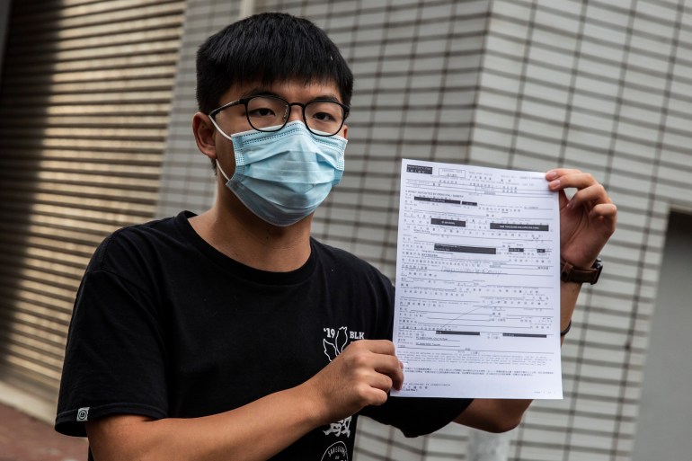 Joshua Wong speaks to the media while holding up a bail document after leaving Central Police Station in Hong Kong on September 24, 2020, after being arrested for unlawful assembly related to a 2019 protest against a government ban on face masks (Photo by ISAAC LAWRENCE / AFP) (AFP)