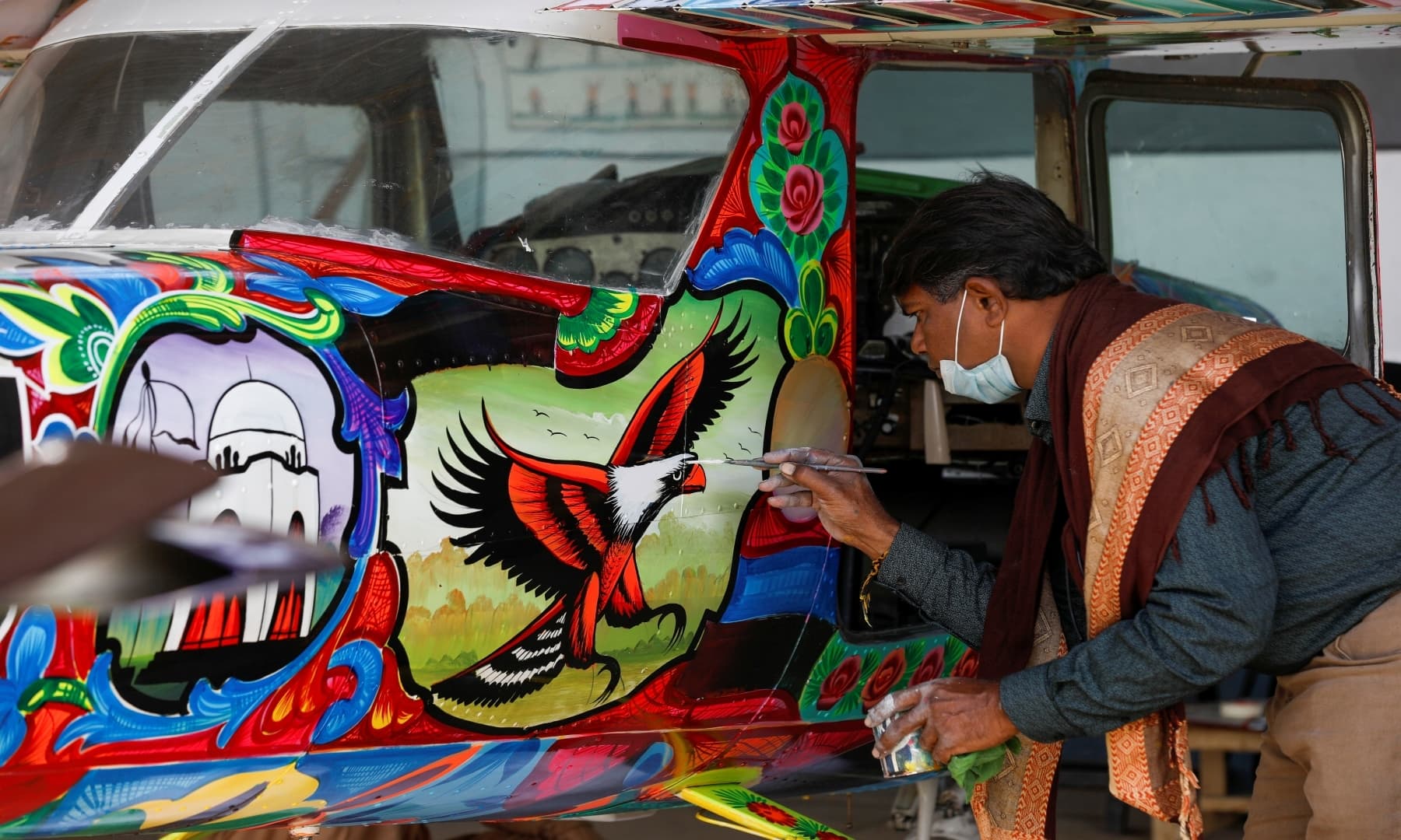 Painter Haider Ali paints Pakistani truck art on a two-seater Cessna aircraft at the Jinnah International Airport, Karachi, Dec 30, 2020. — Reuters