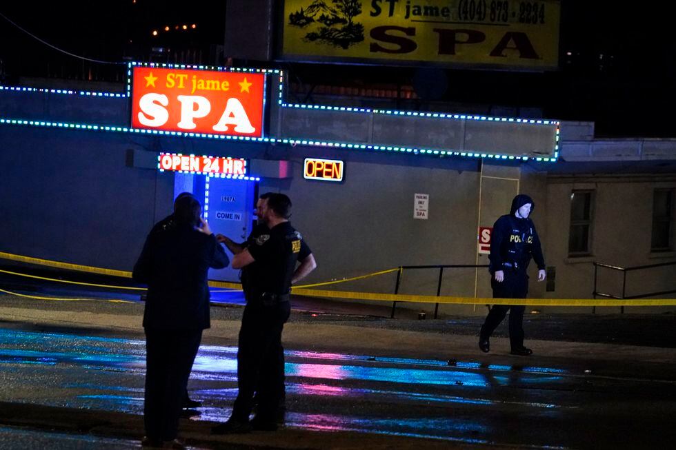 Law enforcement officials confer outside a massage parlor following a shooting on Tuesday,...