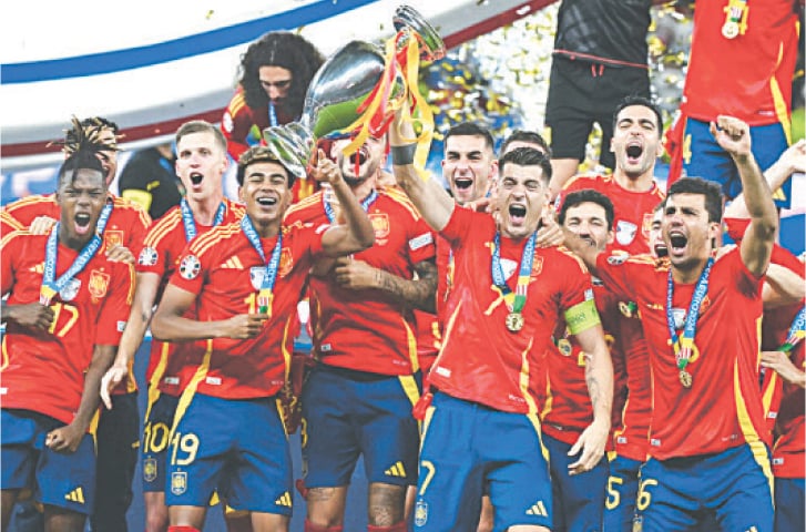  BERLIN: Spain’s Alvaro Morata raises the trophy as his team celebrates after beating England 2-1 to win the UEFA Euro 2024 championship, on Sunday.—AFP 