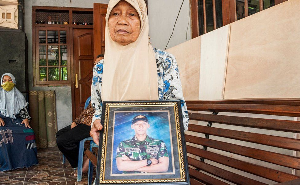 Sarikem holds a photo of her grandson Gunadi Fajar Rahmanto at their home in Yogyakarta on April 26, 2021