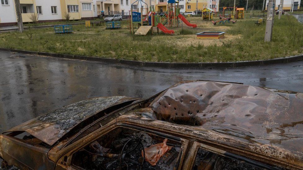 Distinctive marks from a cluster munition in the roof of a car next to a playground in Kharkiv (Joel Gunter/BBC)