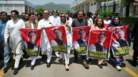 Getty Images Parliamentarians of the Pakistan Tehreek-e-Insaf (PTI) party, carry posters of jailed former prime minister Imran Khan, during a protest outside the Parliament house in Islamabad on July 18, 2024
