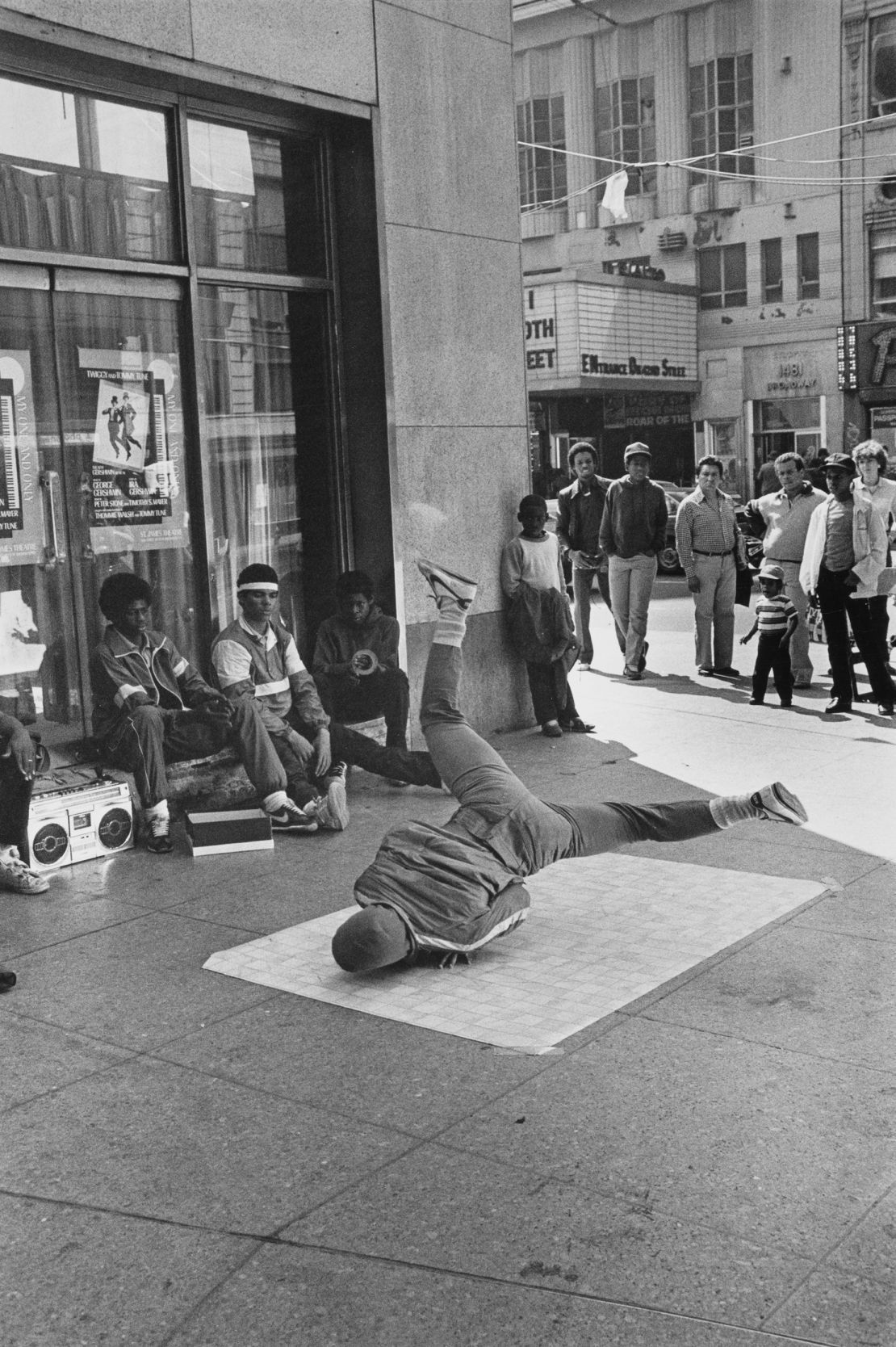 A crowd gathers to watch a youth breakdancing on a piece of linoleum in 1980 in New York City's Times Square.