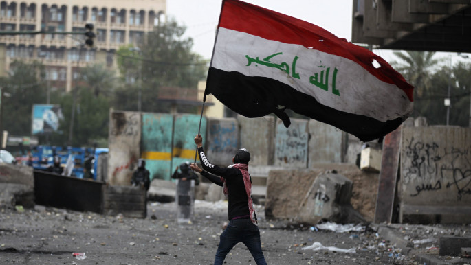 An Iraqi protester waves the national flag amid clashes with riot police at Baghdad's al-Khilani Square on February 19, 2020 during ongoing anti-government demonstrations. (Photo by AHMAD AL-RUBAYE / AFP) (Photo by AHMAD AL-RUBAYE/AFP via Getty Images)