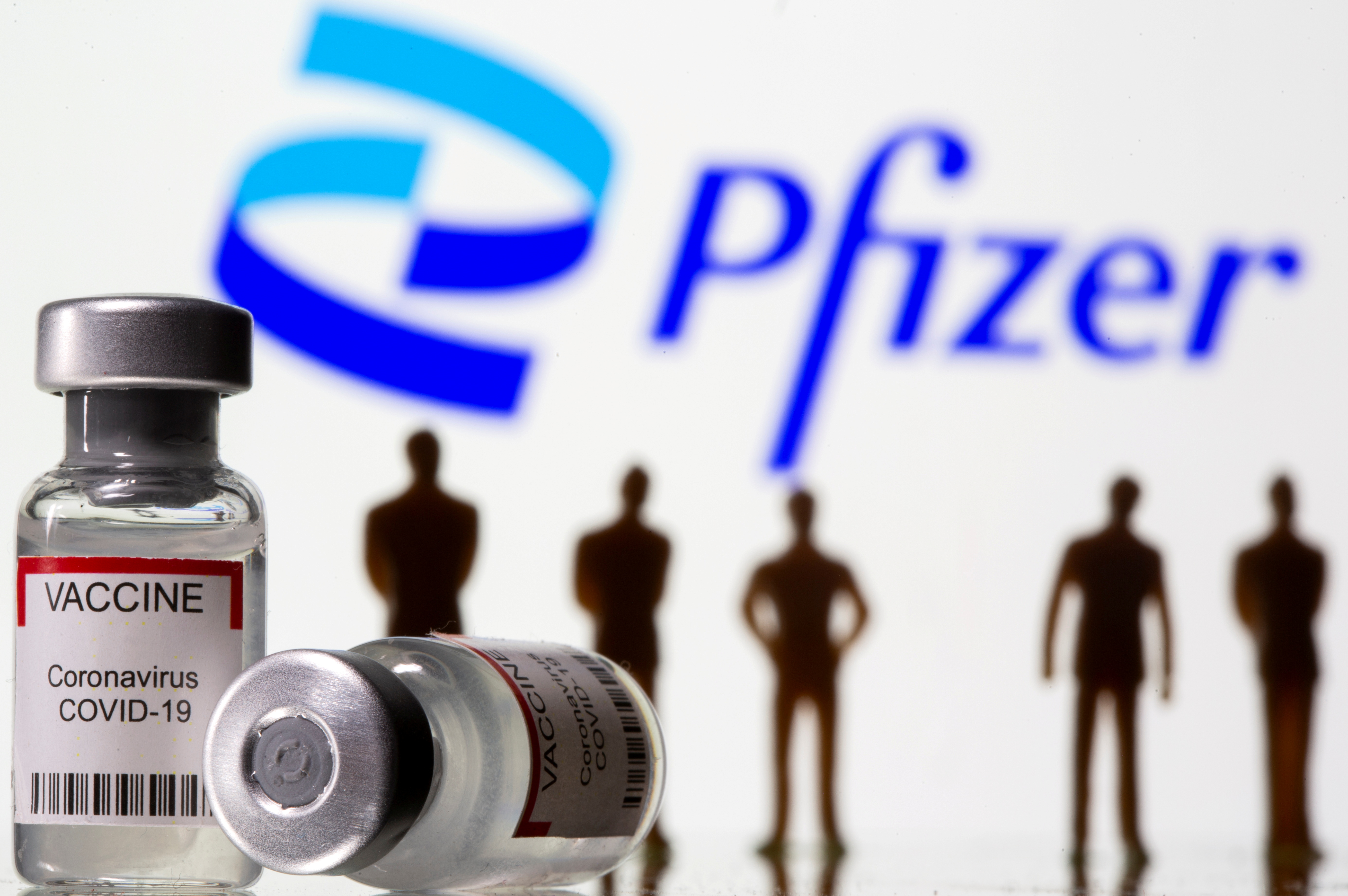 Syringe and vial labelled coronavirus disease (COVID-19) vaccine and small toy figures are seen front of displayed new Pfizer logo in this illustration taken, June 24, 2021. REUTERS/Dado Ruvic/Illustration