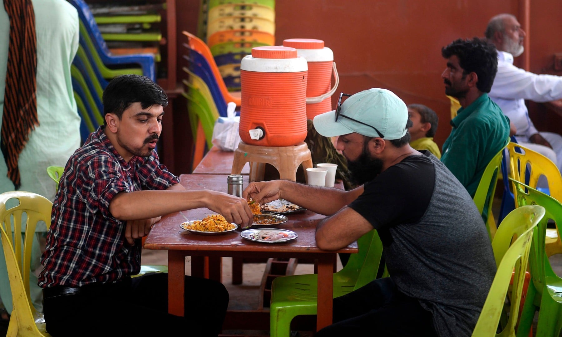 People eat at a restaurant in Karachi on August 10 after the government announced it would be lifting most of the country's remaining coronavirus restrictions. — AFP