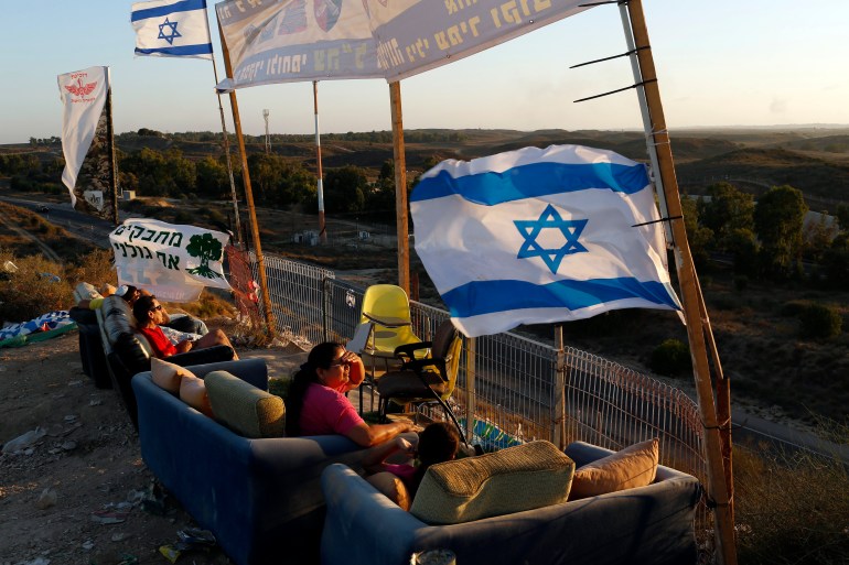 Israelis sit on a hill, overlooking the Gaza Strip, as they watch the Israeli army's assault on Gaza on August 2, 2014 [File: Siegfried Modola/Reuters]