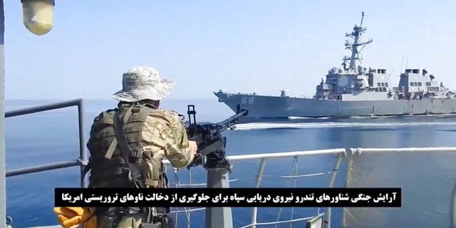 This frame grab from a video released by Iran's paramilitary Revolutionary Guard on Wednesday, Nov. 3, 2021, shows a Guard soldier on a speed boat in front of a U.S warship amid the seizure of a Vietnamese-flagged oil tanker in the Gulf of Oman. Iran seized the tanker in the Gulf of Oman last month and still holds the vessel, two U.S. officials told The Associated Press on Wednesday, revealing the latest provocation in Mideast waters as tensions escalate between Iran and the United States over Tehran's nuclear program. (Revolutionary Guard via AP)