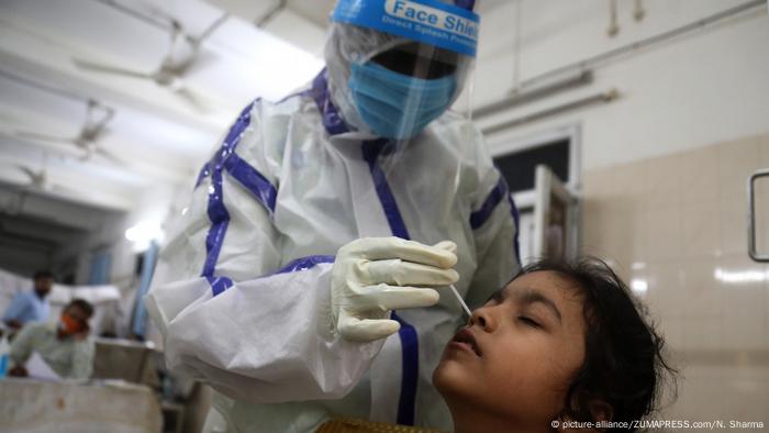 A health worker wearing protective suit collects nasal swab sample from a woman for Covid-19 Rapid Antigen test at a testing center