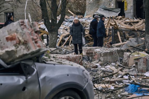 People stand in front of a heavily damaged building