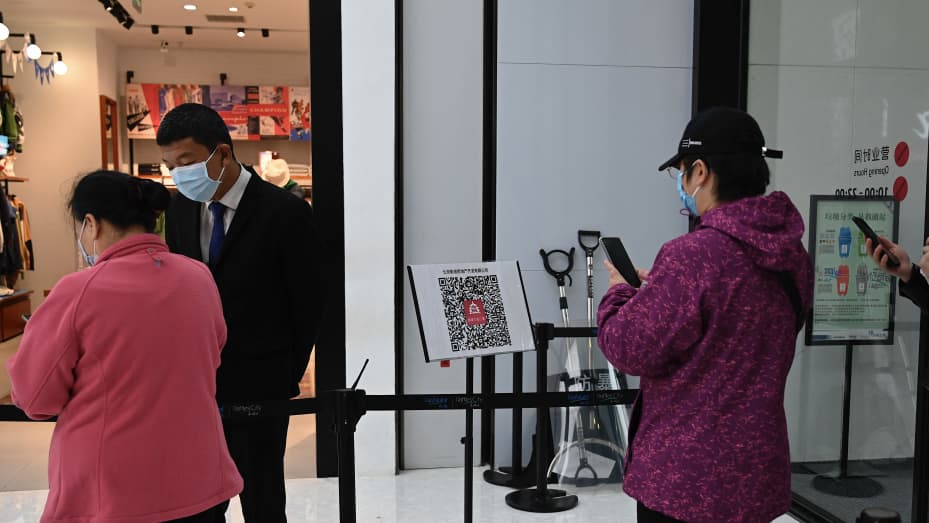 People scan a QR health code as a preventive measure against the Covid-19 coronavirus, before entering a shopping mall in Beijing on November 2, 2021.