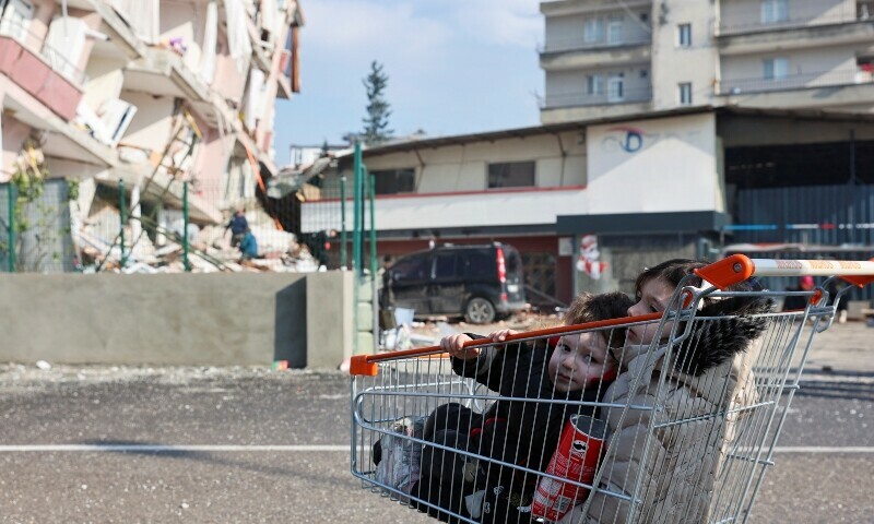 <p>Children sit in a shopping cart near rubble following an earthquake in Hatay, Turkiye, February 7, 2023. — Reuters</p>