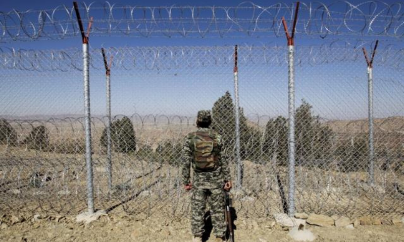 A Pakistani soldier stands guard along the fence at an outpost on the Pak-Afghan border. — Reuters/File