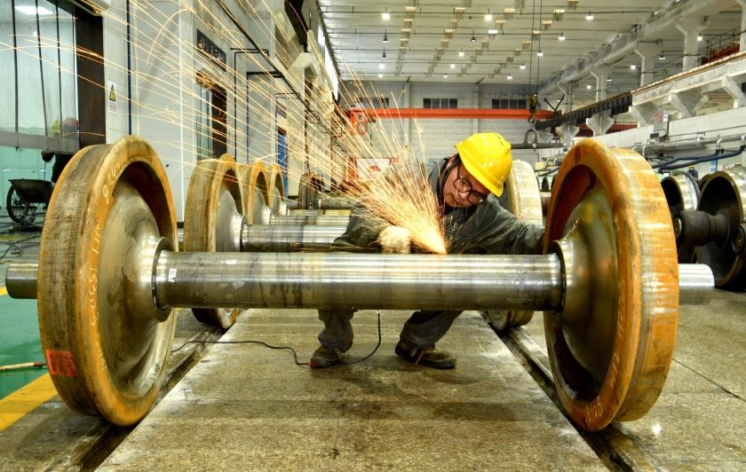 A Chinese worker in a hardhat works on an axle in a Chengdu, Sichuan factory in 2021