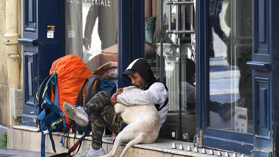 A homeless man hugs his dog as he sits along a deserted street on March 18, 2020.