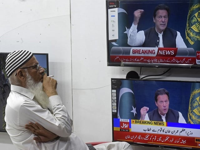 a man listens to pakistan s prime minister imran khan addressing the nation on television at a market in karachi march 31 2022 photo afp