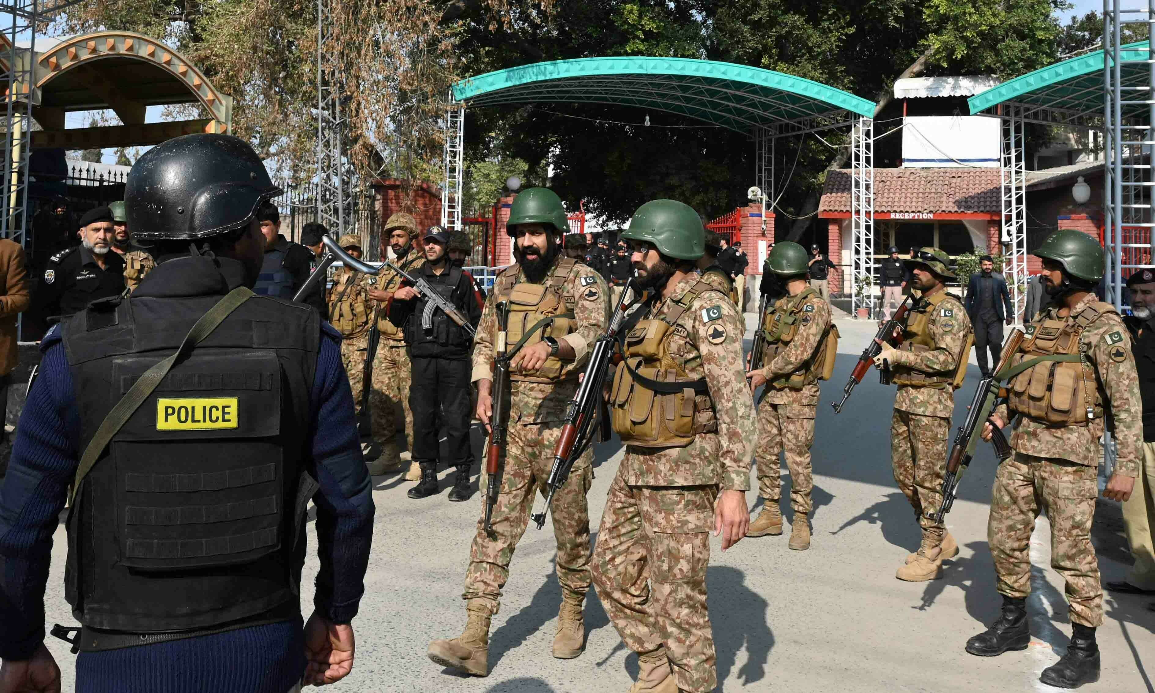 <p>Security personnel stand guard outside the police headquarters after a blast in Peshawar on January 30. — AFP</p>