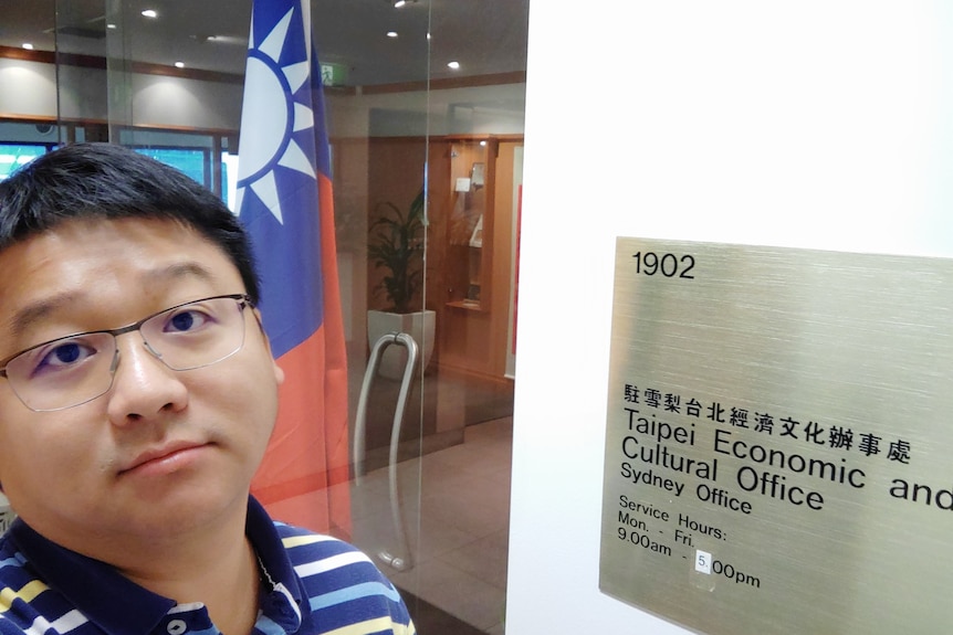 Peter Huang poses for a photo next to a sign that reads Taipei Economic and Cultural Office.