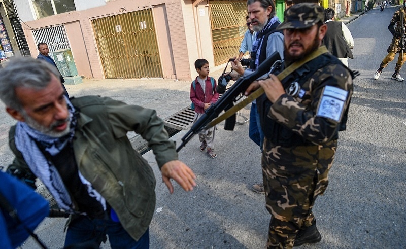A member of the Taliban special forces pushes a journalist (L) covering a demonstration by women protesters outside a school in Kabul on Thursday. — AFP