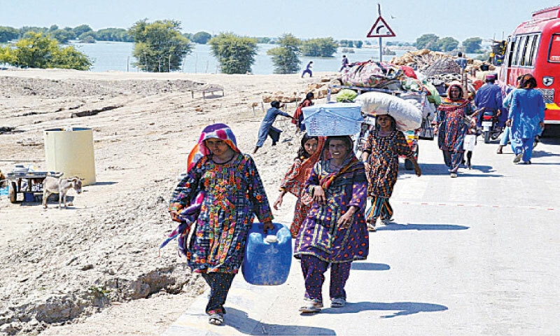 <p>PEOPLE migrating from their flooded villages in Jamshsoro district arrive in Sehwan to take shelter in relief camps.—INP</p>