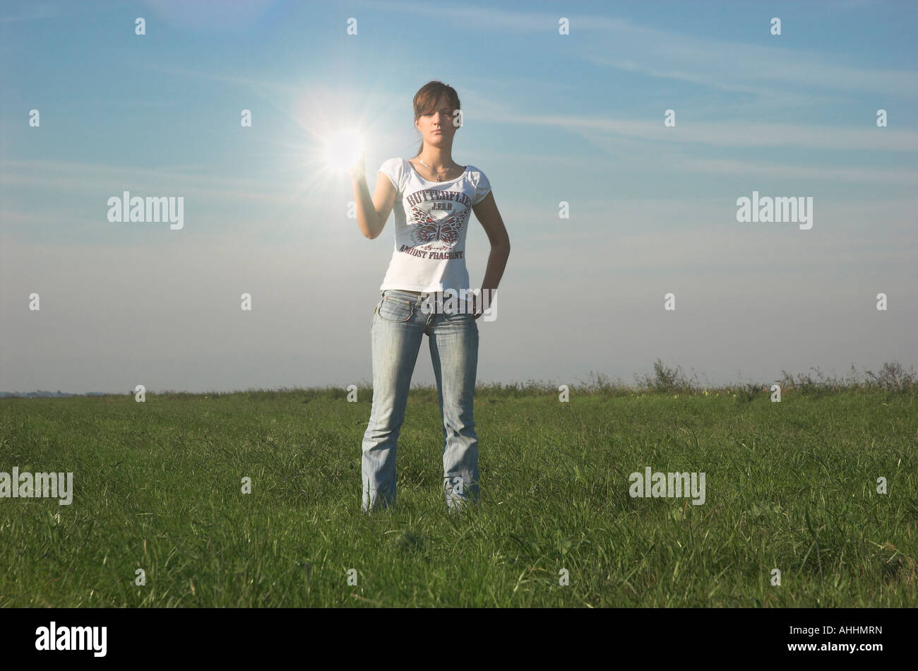 young-woman-standing-in-field-holding-mirror-sunlight-reflecting-in-AHHMRN.jpg