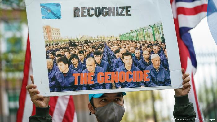 A protester holds a sign saying 'Recognize the Genocide'