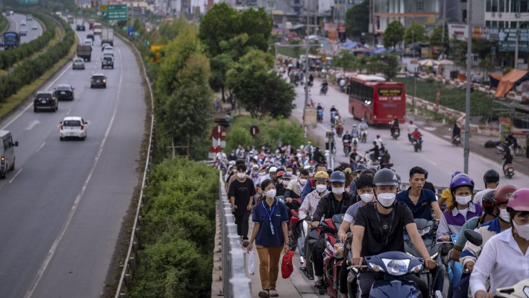 Large groups of workers walking and biking up a street towards the Van Trung Industrial Park in Vietnam.