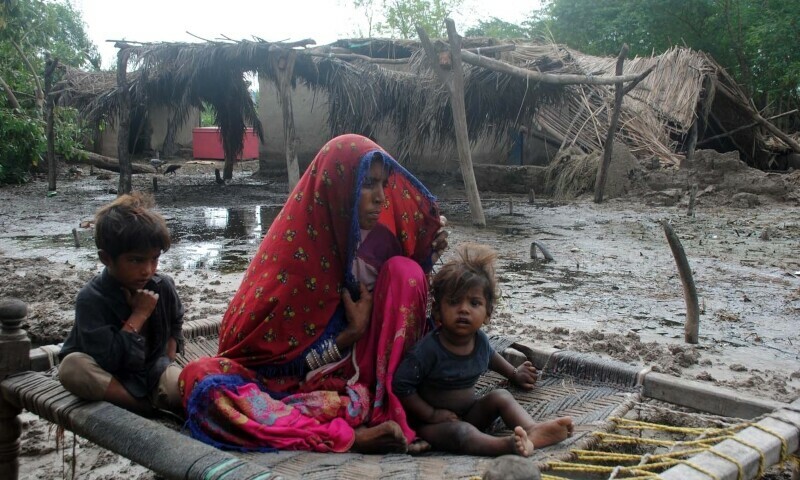 A woman with her children in a rain-affected village in Matiari on Saturday. — Umair Ali