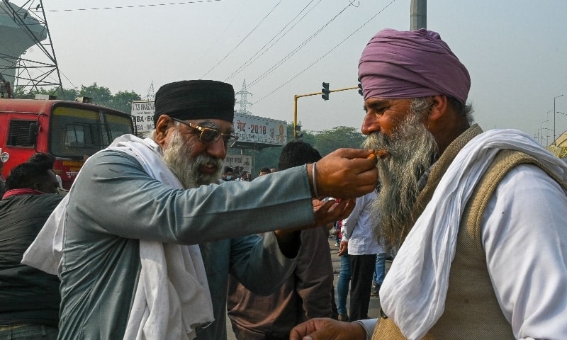 Farmers feed sweets to each other to celebrate after India's Prime Minister announced to repeal three agricultural reform laws that sparked almost a year of massive protests by farmers around the country in Ghaziabad on November 19. — AFP