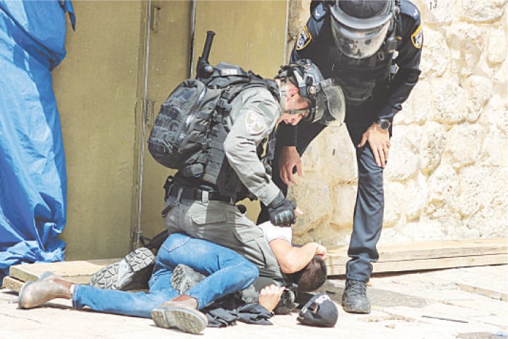 ISRAELI police detain a Palestinian during violence at the compound that houses Al Aqsa mosque on Monday.—Reuters
