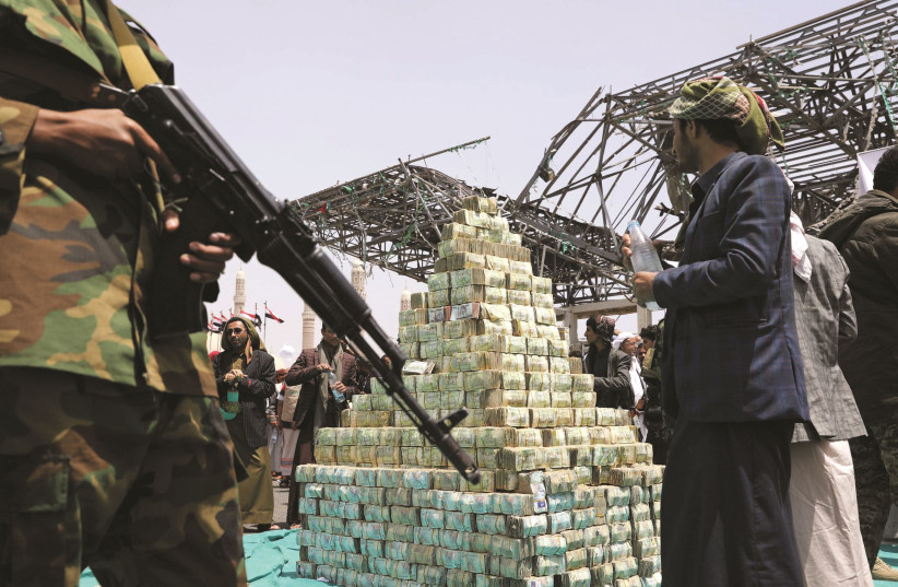 HOUTHI FOLLOWERS stand by bills of Yemeni currency during a ceremony in Sana’a in September 2020 to collect supplies for their fighters battling government forces. (photo credit: KHALED ABDULLAH/ REUTERS)