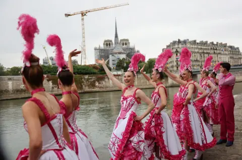 Wang Dongzhen/Getty Images Dancers in pink and white dresses perform on the riverside during the opening ceremony of the 2024 Summer Olympics on July 26, 2024 in Paris, France.