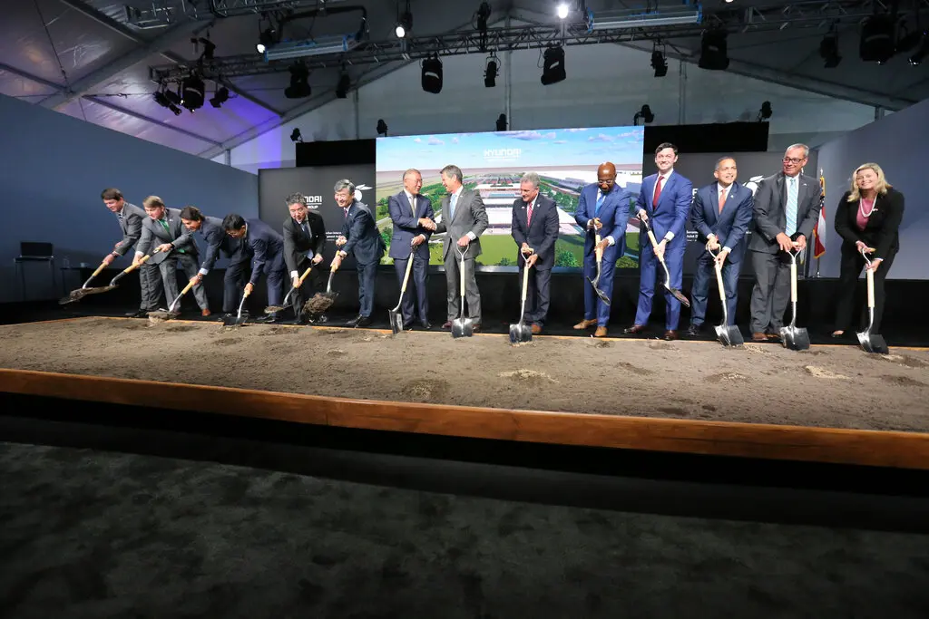 People wearing business suits and holding shovels, some of them digging into the ground. 