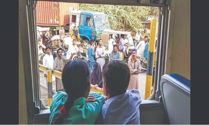 CURIOUS onlookers examine the newly launched KCR train on Wednesday and (right) bemused motorists watch the train pass at a level crossing.—Fahim Siddiqi / White Star