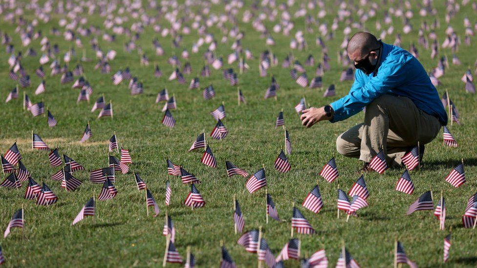 Chris Duncan, whose 75 year old mother Constance died from Covid, seen at September memorial among small US flags to commemorate the Covid dead