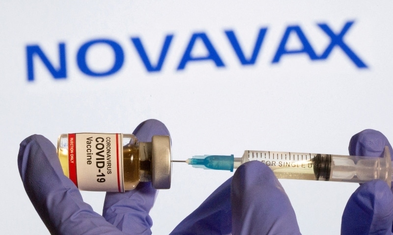 A woman holds a small bottle and a medical syringe in front of displayed Novavax logo in this illustration taken, October 30, 2020. — Reuters