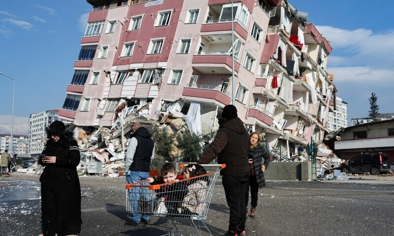 <p>Children sit in a shopping cart near a collapsed building following an earthquake in Hatay, Turkiye, February 7, 2023. — Reuters</p>