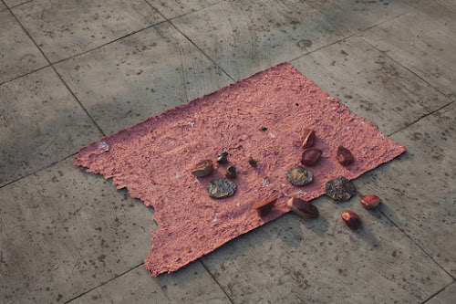 Rajyashri Goody’s “Lal Bhaaji” (2019) represents a dish of the same name eaten by some Dalit communities in Maharashtra. Lal Bhaaji—literally, “red vegetable”—is a widely consumed leafy plant, but Dalits use its name as a code for beef, so as not to let others know what they are eating. Ceramic pieces representing beef, puris and bones are arranged on red paper made of a pulped copy of the Manusmriti, a touchstone of Hindu caste laws, and the bone pieces are stuﬀed with pages from the text. Goody evokes the shame that many Dalits have been conditioned to associate with beef-eating—her own family has turned to vegetarianism, and now scowls at beef—and tries to associate it instead with resistance to caste beliefs. Her use of the Manusmriti as an active “ingredient” in her Lal Bhaaji is an act of assertion and defance.. courtesy rajyashri goody