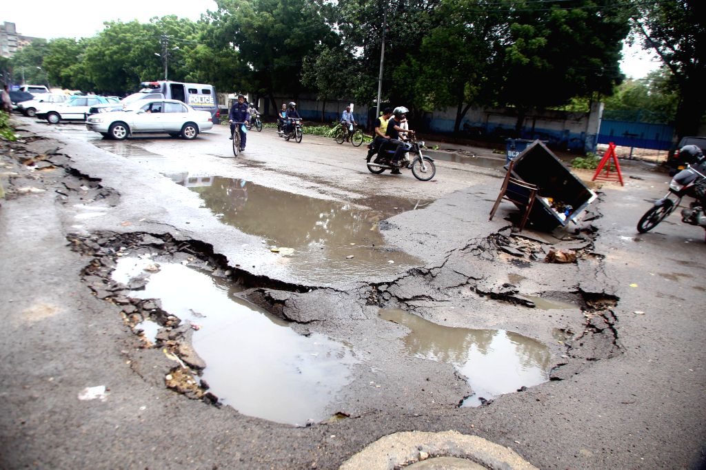 karachi-july-30-2019-people-ride-past-a-damaged-870978.jpg