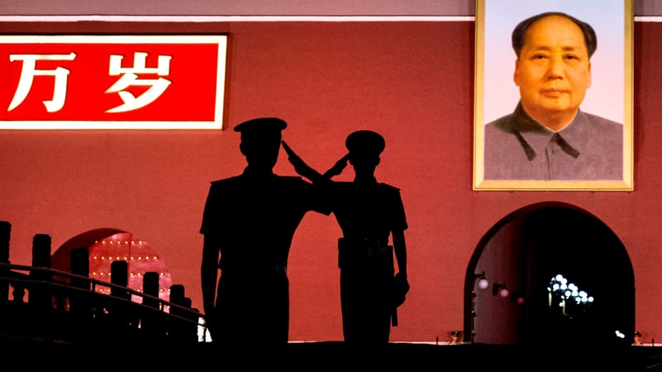 Chinese Paramilitary police officers salute each other as they stand guard below a portrait of the late leader Mao Zedong in Tiananmen Square in Beijing, China.