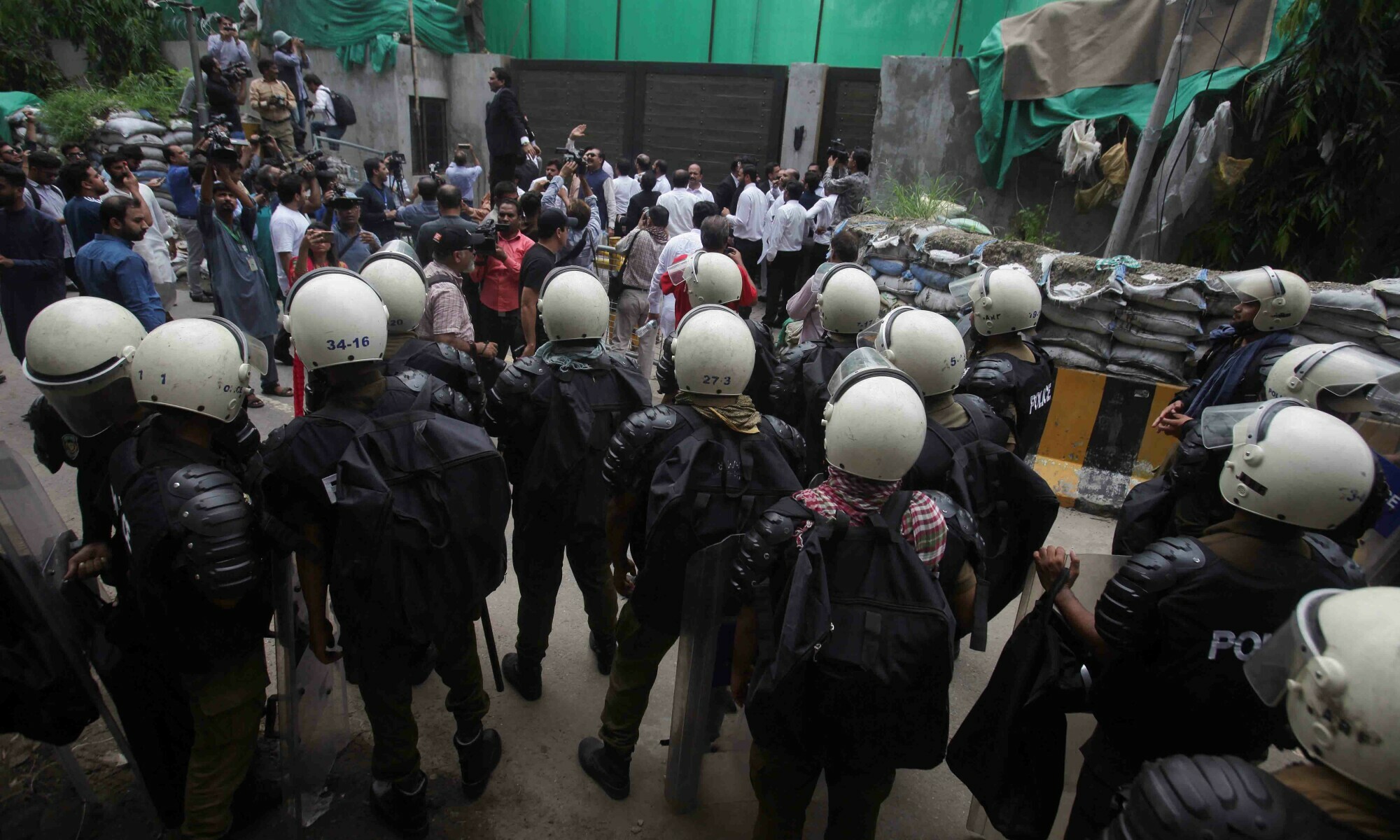 Police officers and members of the media gather following the arrest of PTI chief Imran Khan, outside his residence in Lahore on August 5. — Reuters