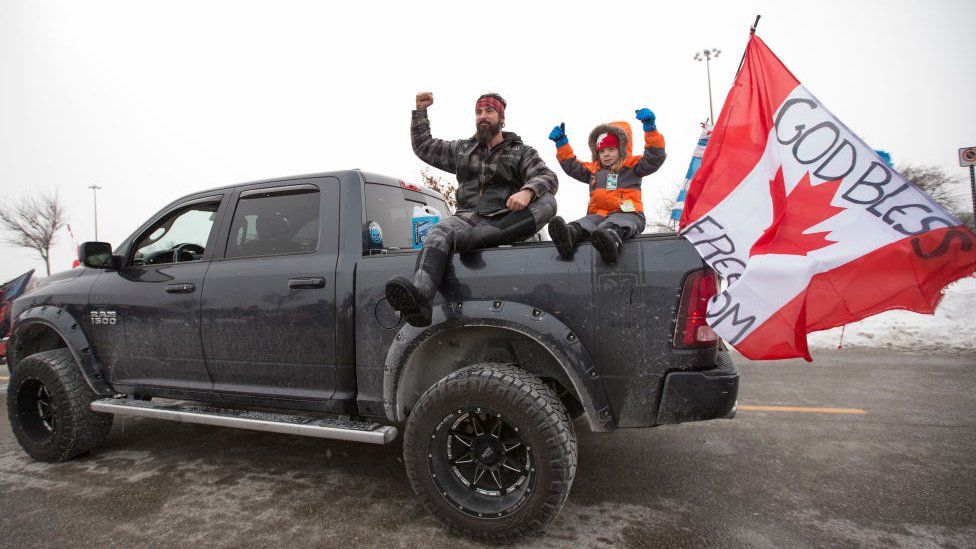 A man and child sit a top the back of a pick up truck which was participating in the convoy.