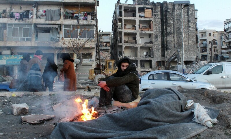A man who evacuated his home warms up next to a fire on a street, in the aftermath of the earthquake, in Aleppo, Syria February 8, 2023. — Reuters